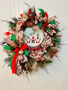 a christmas wreath hanging on the side of a wall with decorations and ribbons around it