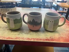 three coffee mugs sitting on top of a table