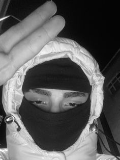 a person wearing a hood and holding up their hand