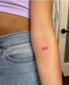 a woman's arm with the word ros tattooed on her left side ribcage