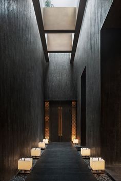 an empty hallway with white chairs and lights on either side of the room is lit by two lamps