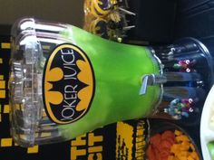 there is a green juice machine with batman logo on the front and yellow lettering on the back