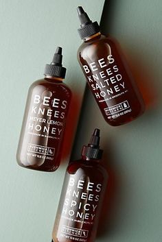 three bottles of bee's knees honey and honey seed oil on a green surface