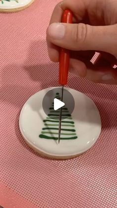 a person is using a needle to cut a christmas tree on a white and green plate