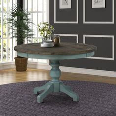 a small round table sitting on top of a rug in front of a gray wall