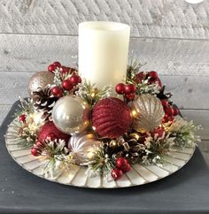 a candle sits on top of a plate with christmas decorations and baubles around it