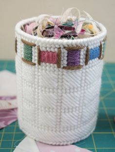 a white basket filled with lots of different colored thread