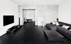 a black and white living room with couches, coffee table and television on the wall