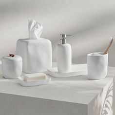 white bathroom accessories including soap dispenser, toothbrush holder and cup