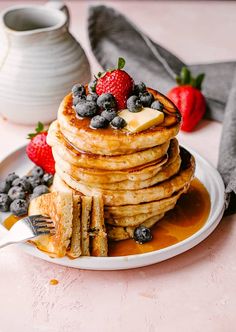 a stack of pancakes with syrup and berries on top