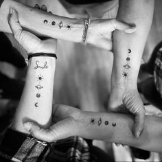 three people holding hands with tattoos on them