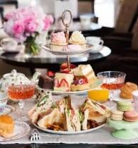 a table topped with plates and cups filled with food next to cakes, cupcakes and muffins