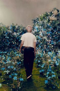 a man walking through a field of blue flowers