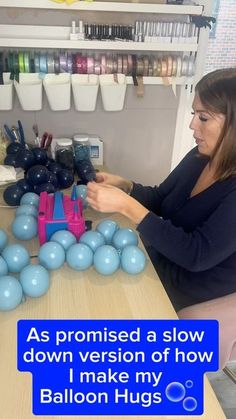 a woman sitting at a table with balloons in front of her and the caption says, as provided a slow down version of how i make my balloon hugs