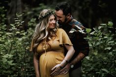 a pregnant woman in a yellow dress standing next to a man wearing a flower crown