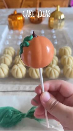 a hand holding a candy lollipop with the words cake ideas on it and pumpkins in the background