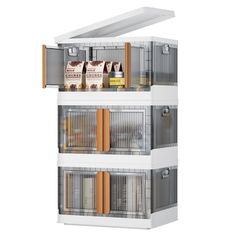 three tiered white bird cage with food in the bottom section and two shelves on each side