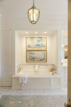 a bathroom with a tub, sink and paintings on the wall