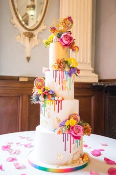 a multi - tiered wedding cake with flowers and rainbow drips on the side