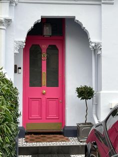 a car is parked in front of a pink door