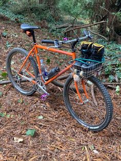 an orange bike parked on the side of a dirt road in front of some trees