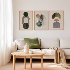 a living room with white couches and paintings on the wall above them, along with a coffee table