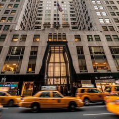 taxi cabs and taxis drive past the entrance to an office building in new york city