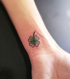 a small four leaf clover tattoo on the wrist