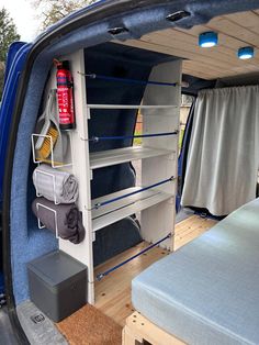 the back end of a blue van with shelves in it