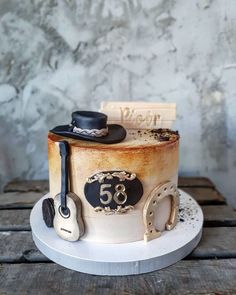 a cake that is sitting on top of a wooden table with a hat and guitar