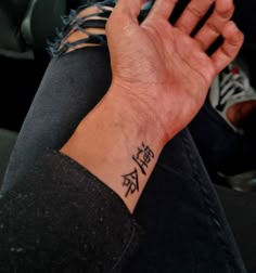 a person with a wrist tattoo holding their hand up