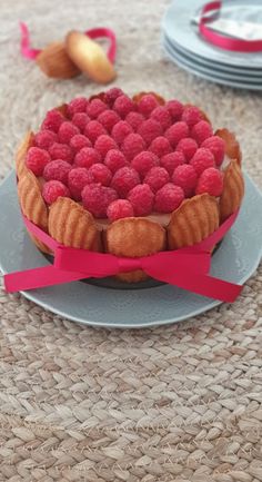 a raspberry pie on a plate with pink ribbon