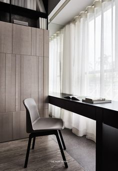 a chair sitting in front of a window next to a desk