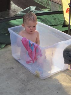 a baby sitting in a plastic container on the ground