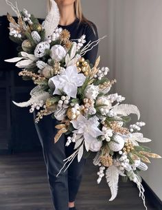 a woman holding a bouquet of white flowers and greenery in front of her face