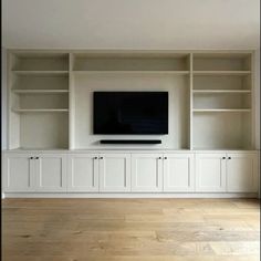 an empty living room with white cabinets and a flat screen tv mounted on the wall