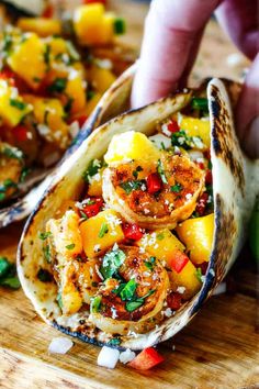 someone is grabbing some food from a tortilla on a cutting board with other foods in the background