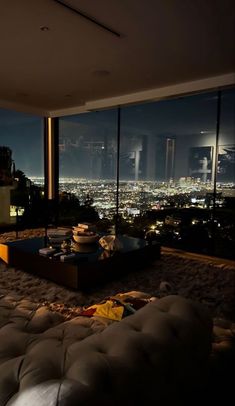 a living room filled with lots of furniture and large windows overlooking the city at night