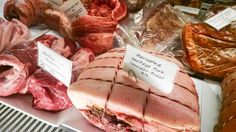 various meats are on display for sale in a market stall, with price tags attached to them