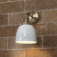 a white light mounted on the side of a brick wall next to a lamp shade