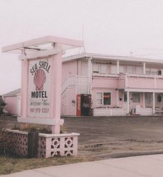 a pink motel sign sitting on the side of a road