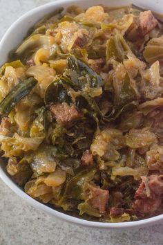 a bowl filled with meat and vegetables on top of a white countertop next to a cup of coffee