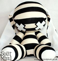 a black and white striped stuffed animal sitting on top of a bed with the caption split mind