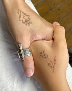 a person holding the hand of another person with small tattoos on their arm and wrist