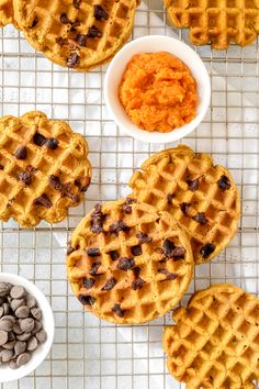 several waffles on a cooling rack with bowls of chocolate chips next to them