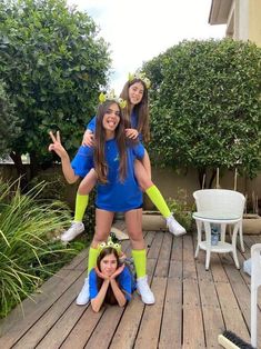 three girls in costumes posing on a deck with their hands up and one girl holding her head