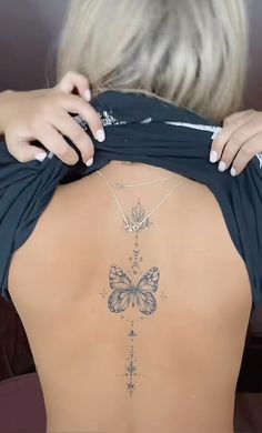 the back of a woman's body with a butterfly tattoo on her lower back