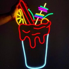 a neon sign that is lit up in the dark with some ice cream on it