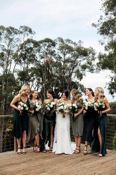 a group of women standing next to each other on a wooden floored area with trees in the background