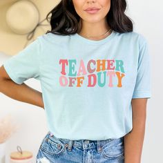 a woman wearing a t - shirt that says teacher off duty in multicolored letters